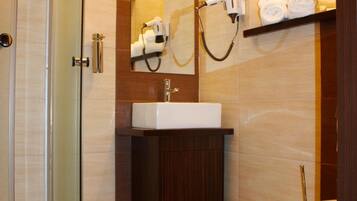 Een moderne badkamer met een douche met glazen wand, een witte wastafel en een toilet.