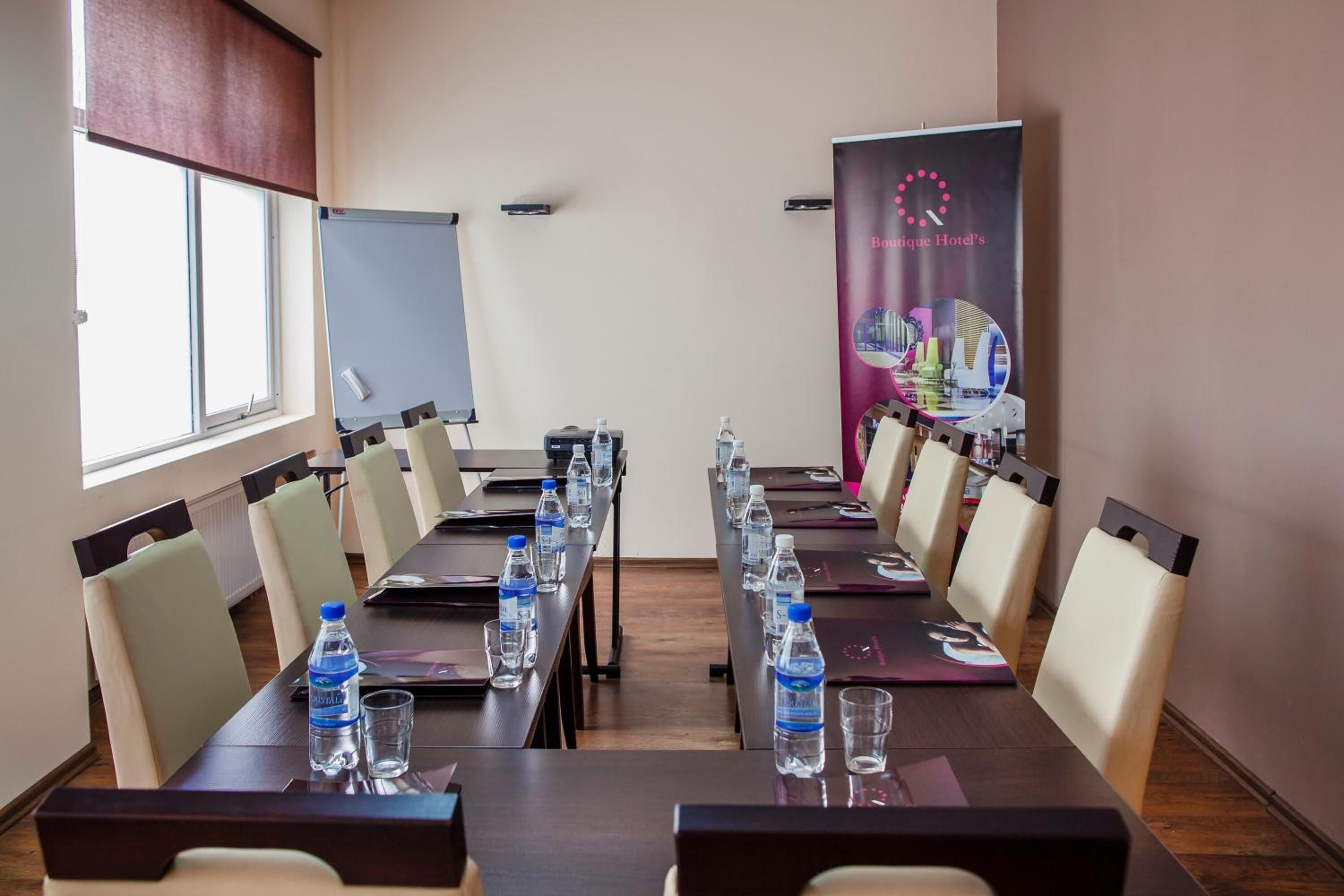 Ein Konferenzraum mit langem Tisch, Stühlen, Wasserflaschen und einem Banner für das Boutique Hotel.
