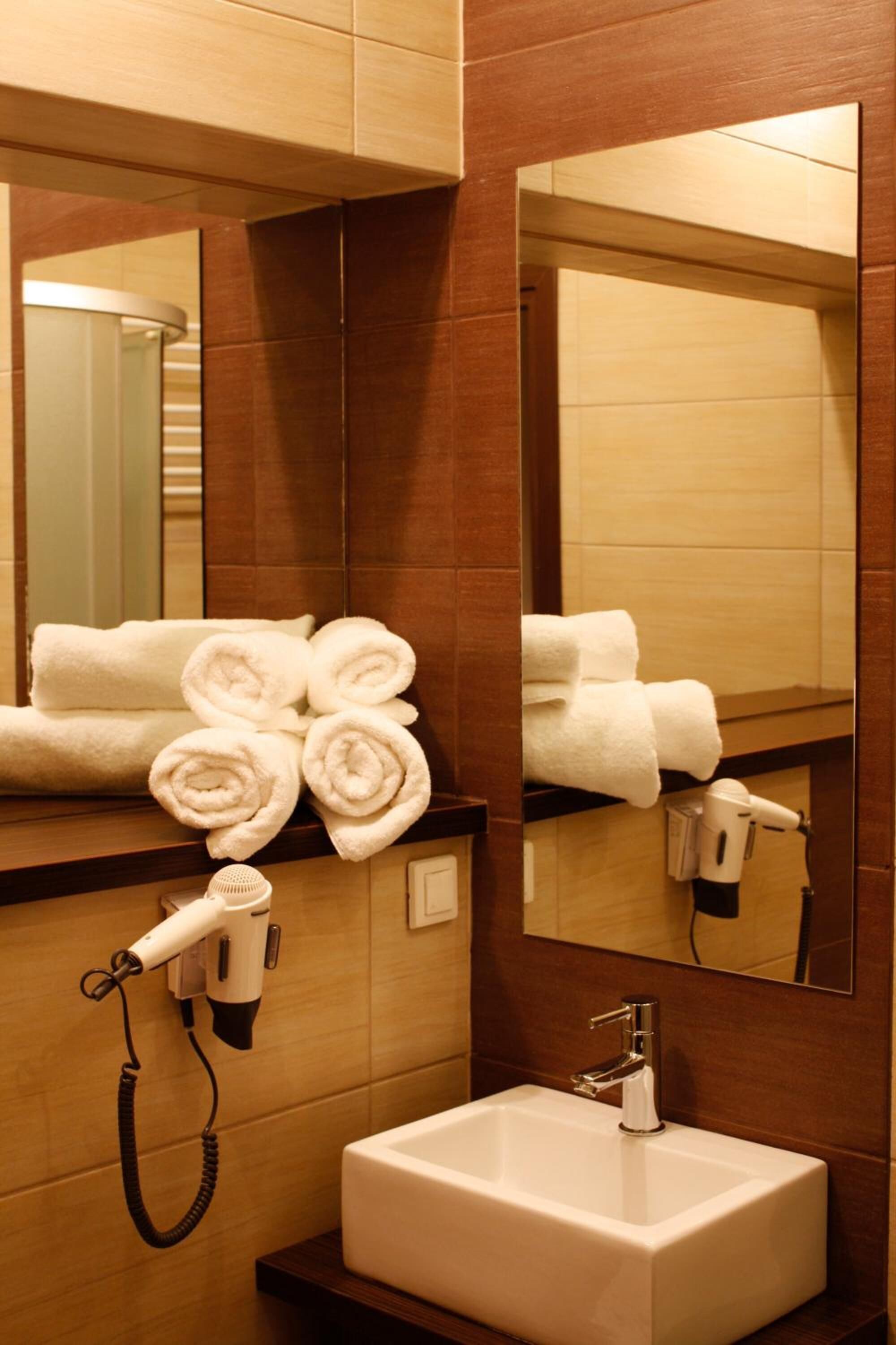 A bathroom with a sink, a hairdryer, and towels neatly arranged on the counter.