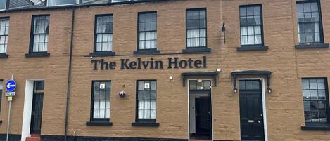 Un edificio de dos pisos con el letrero "The Kelvin Hotel" en la fachada.