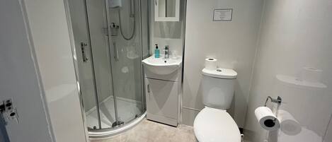 Een moderne badkamer met een glazen douchecabine, een wit wastafelmeubel en een toilet.