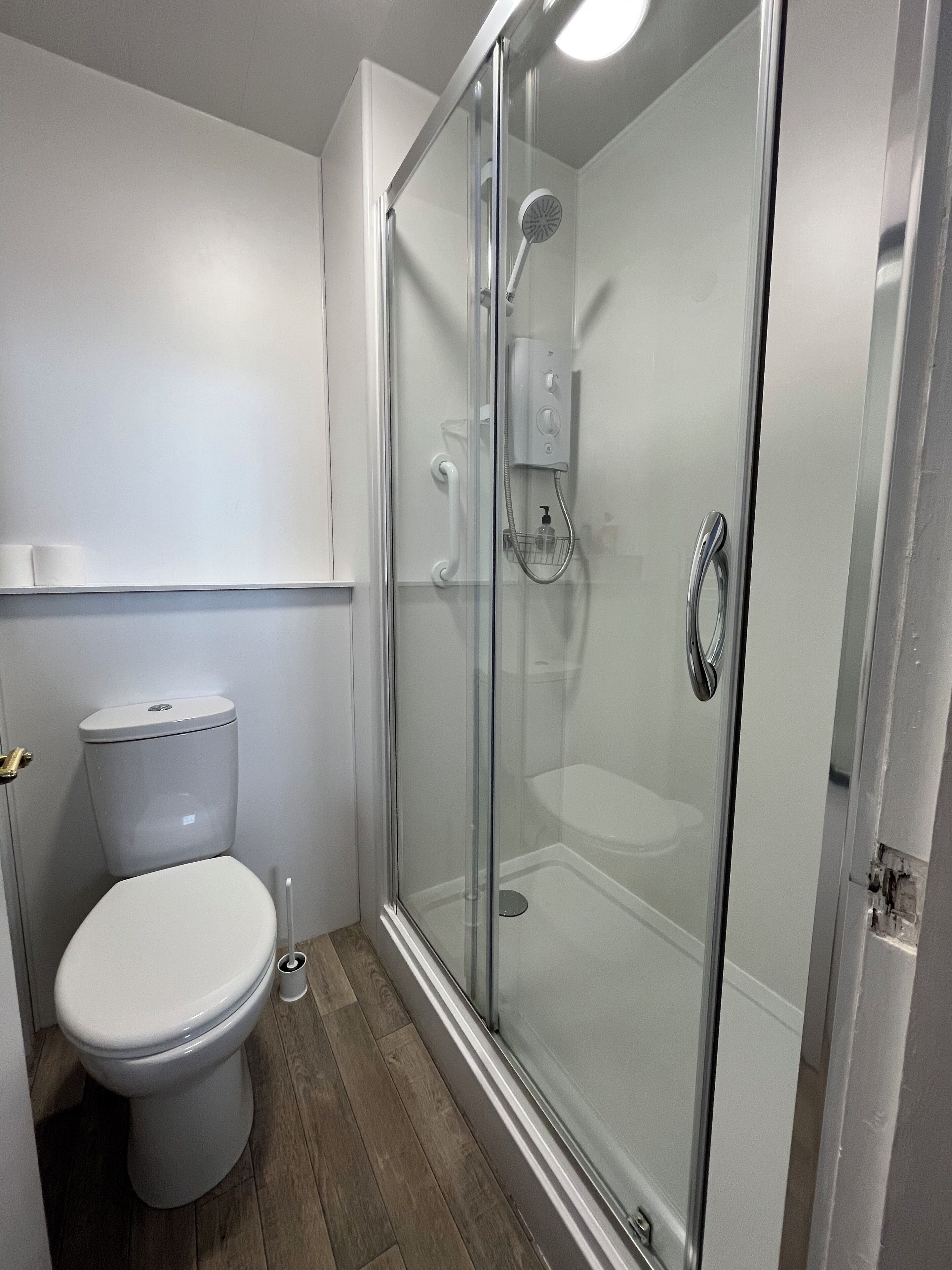 A bathroom with a toilet, a glass-enclosed shower, and a white sink.