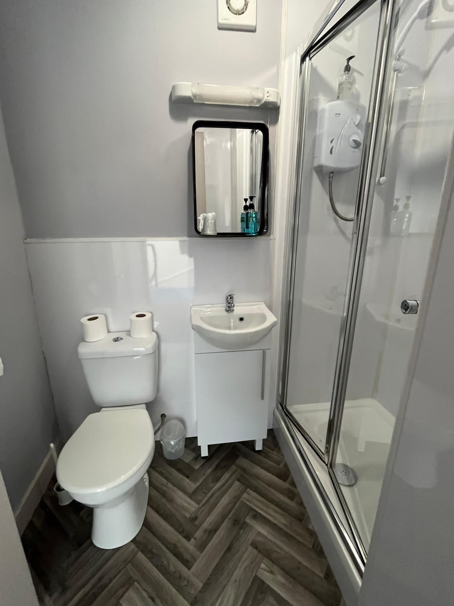 A compact bathroom with a toilet, sink, and glass shower enclosure.