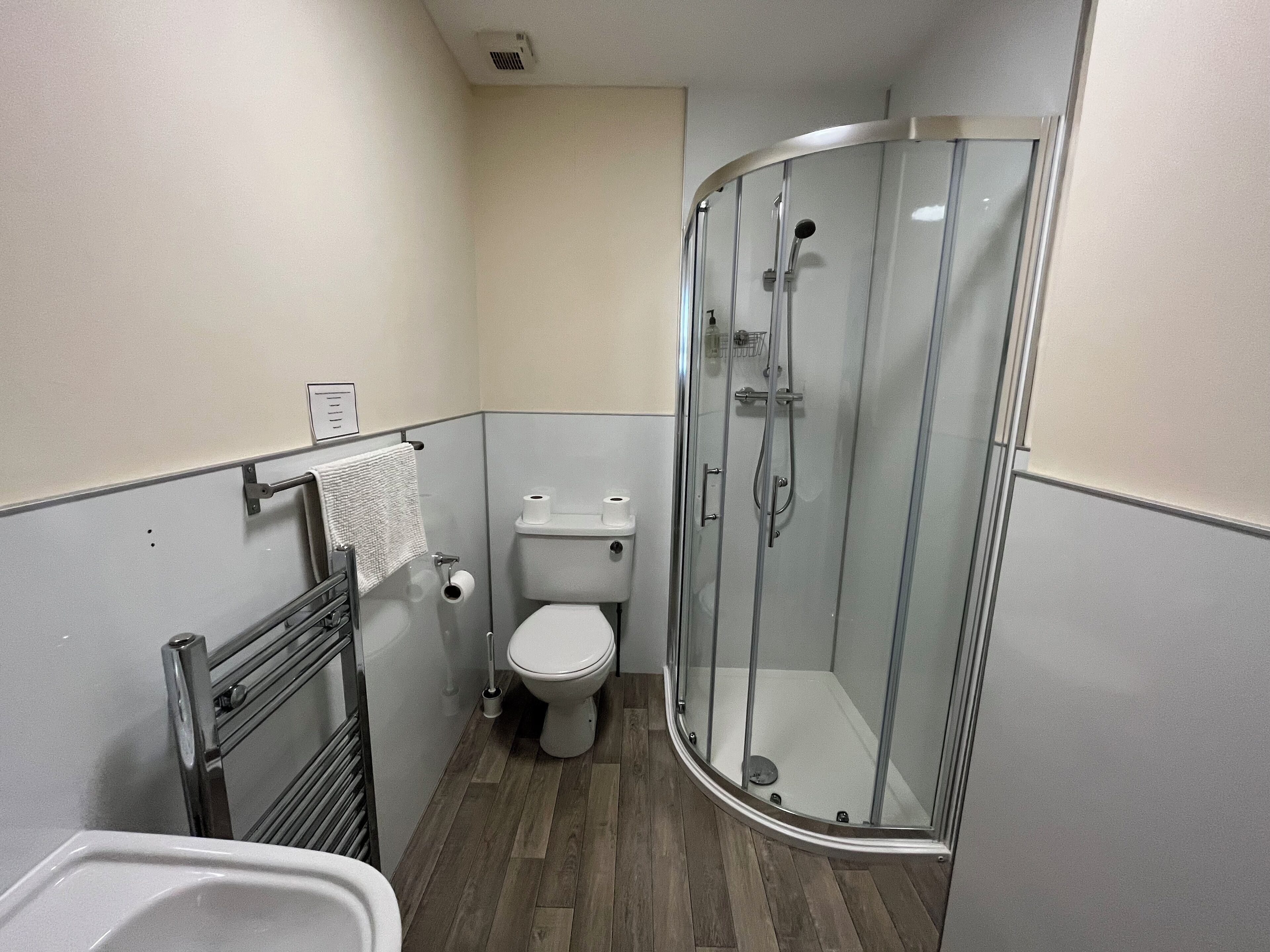 Une petite salle de bain comprenant des toilettes, une douche à parois de verre et un porte-serviettes.