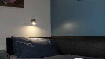 Une chambre à coucher avec un lit, des oreillers, une table de chevet et des œuvres d’art murales.
