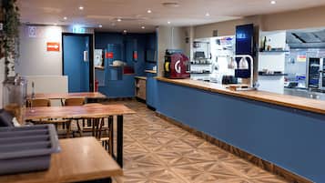 Un restaurante moderno con mostrador, zona de asientos y cocina al fondo.