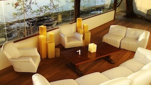 A modern living room with a sofa set, a coffee table, and a chair. There are tall, rectangular vases on the coffee table. - Pousada Martin Pescador (Búzios)