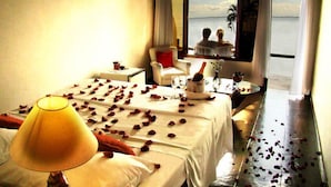 A hotel room with a bed, a table with a bottle and glasses, and a view of the sea. - Pousada Martin Pescador (Búzios)