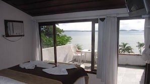 A bedroom with a bed, a window with curtains, and a view of the sea. - Pousada Martin Pescador (Búzios)