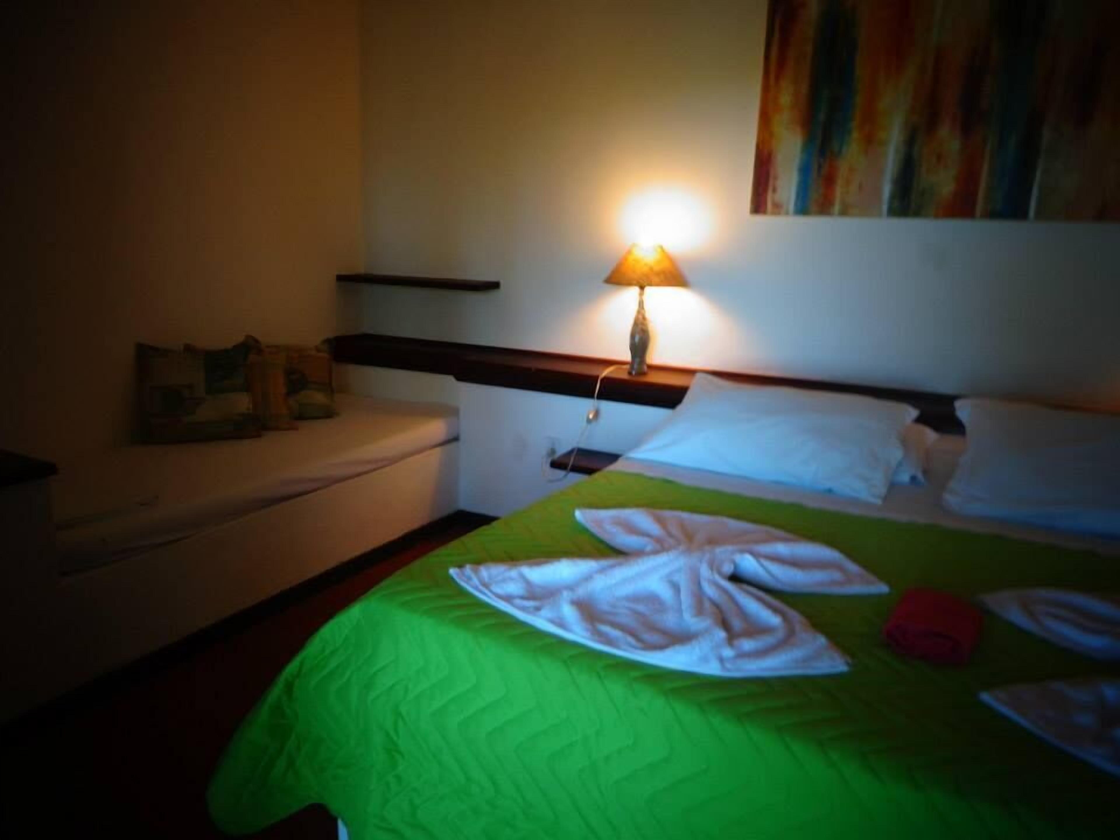 Ett hotellrum med en säng, ett nattduksbord, en lampa och en tavla på väggen.