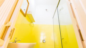 A bathroom with a yellow tiled wall, a white sink, and a mirror.