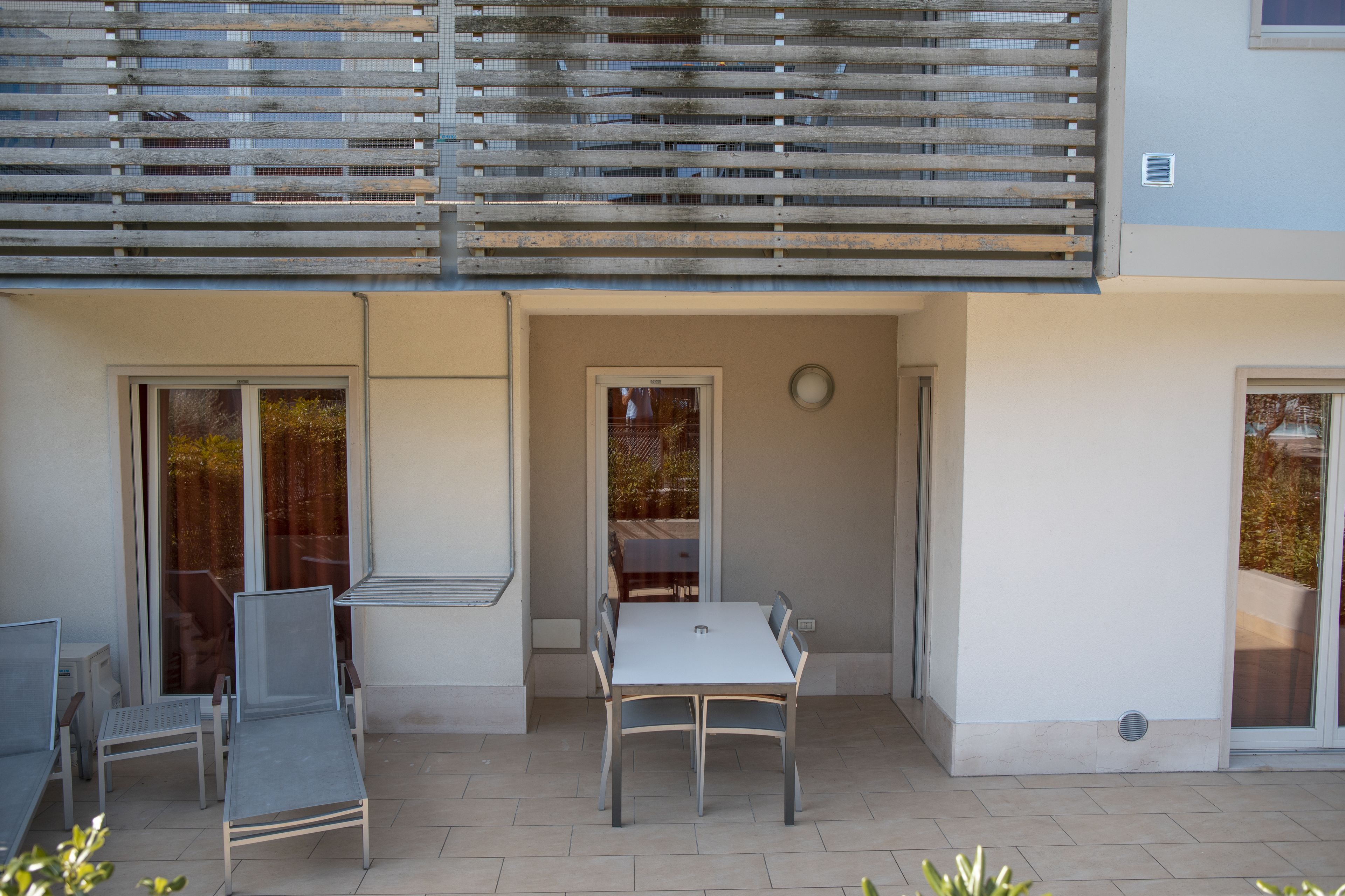 Un espace patio extérieur avec une table et des chaises, un plafond en lambris de bois et une porte-fenêtre coulissante.