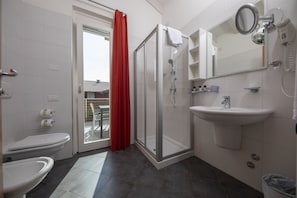 A modern bathroom with a toilet, bidet, shower, and sink.