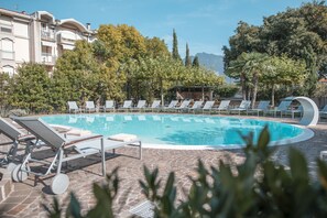 A swimming pool with lounge chairs and a stone patio.