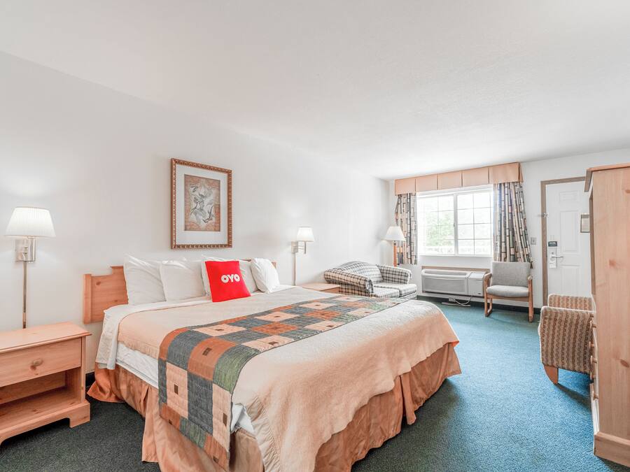 A hotel room with a large bed, a desk, a chair, and a wardrobe.