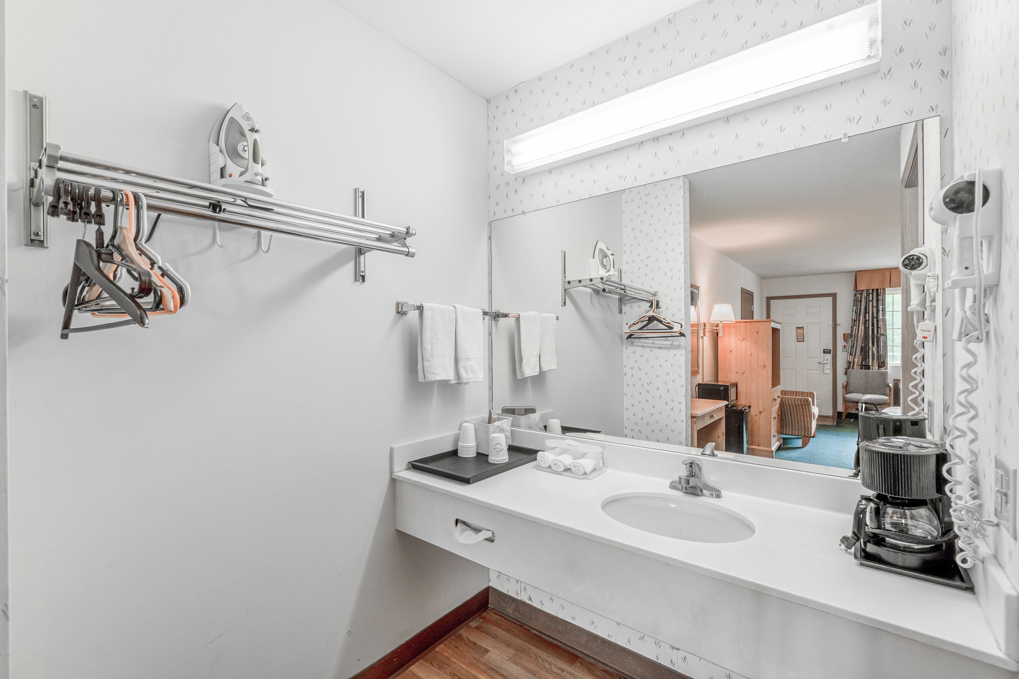 A modern bathroom with a large mirror, towel rack, and a coffee machine.
