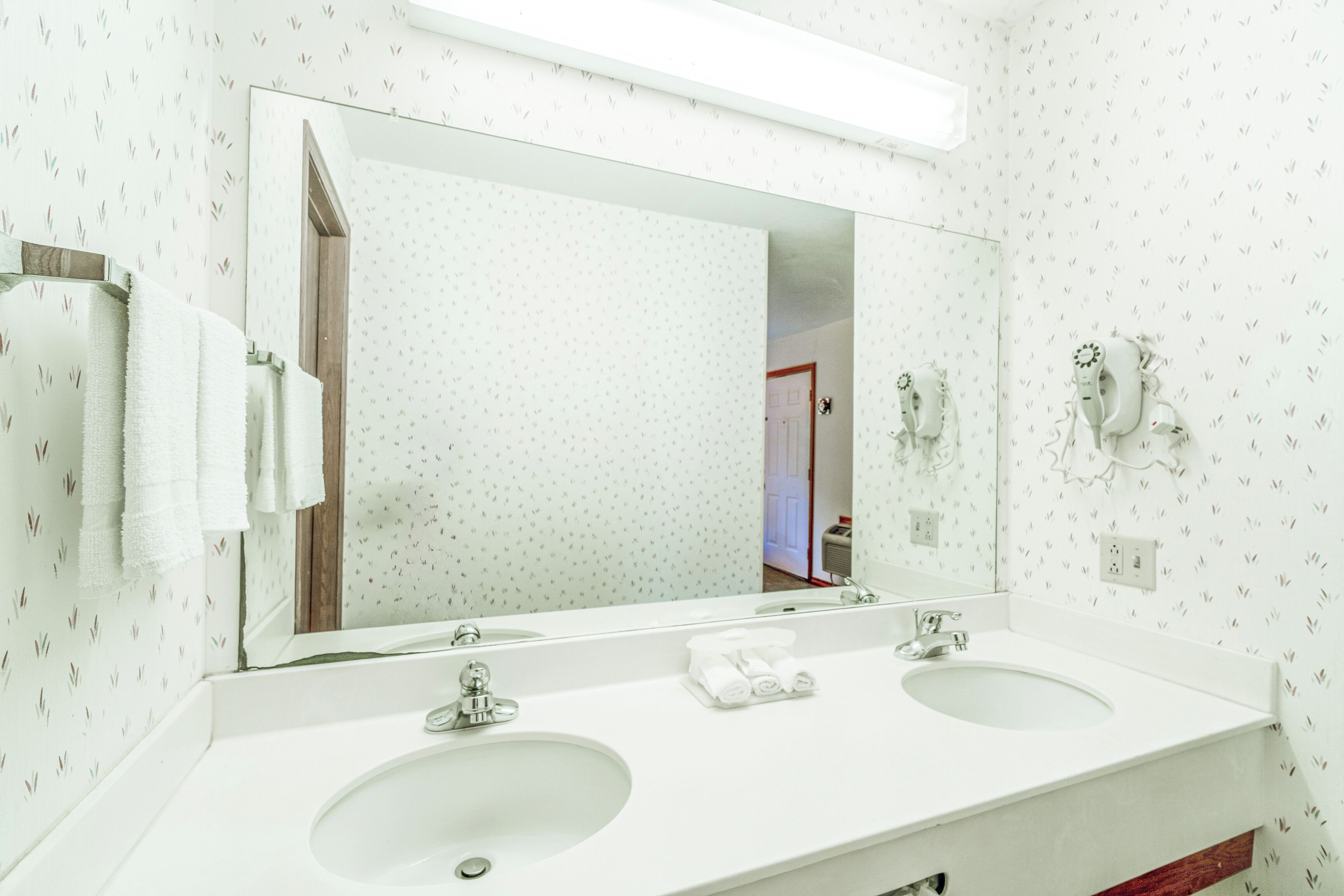 A bathroom with two sinks, a large mirror, and a towel rack.