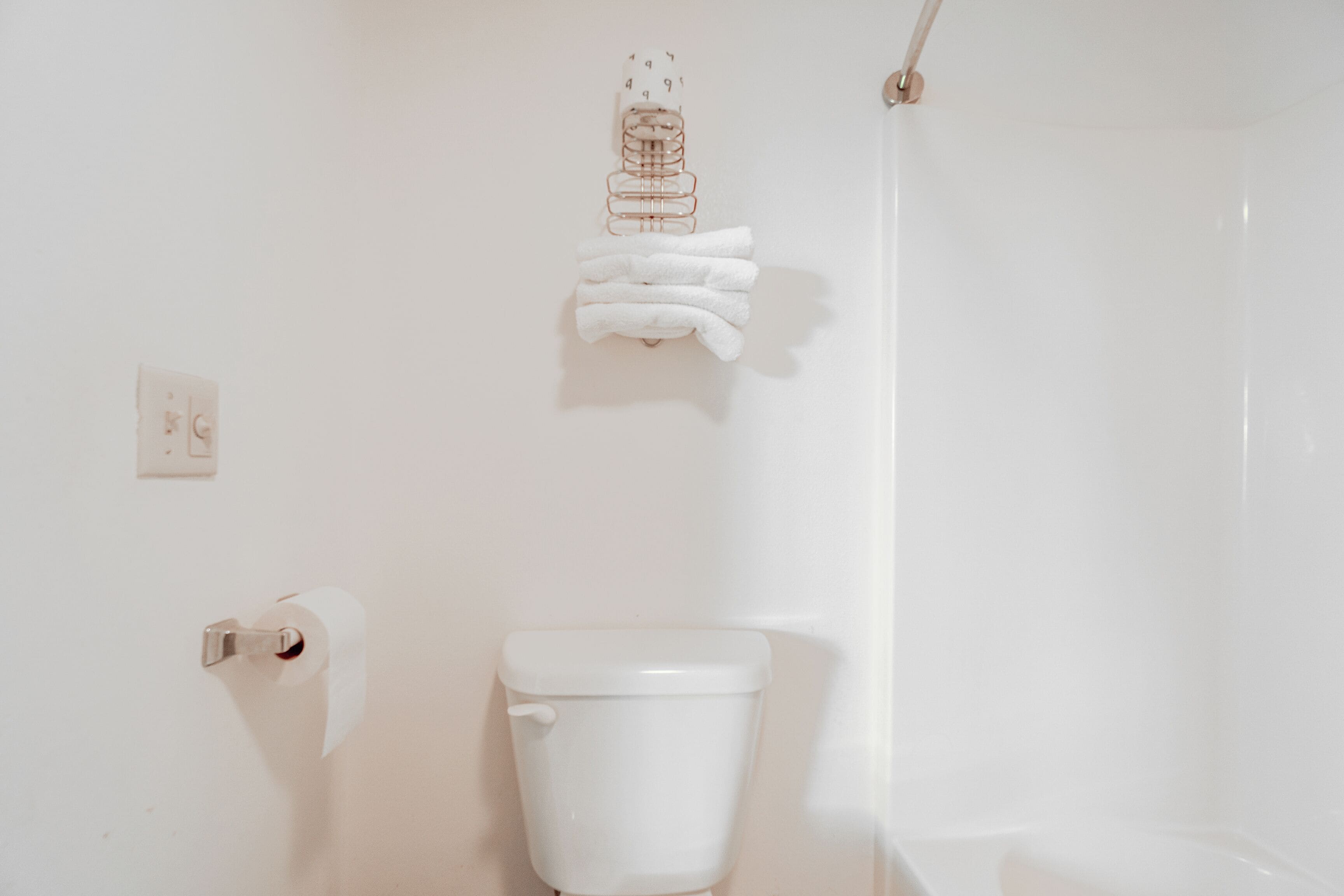 A bathroom with a toilet, a towel rack, and a paper towel dispenser.
