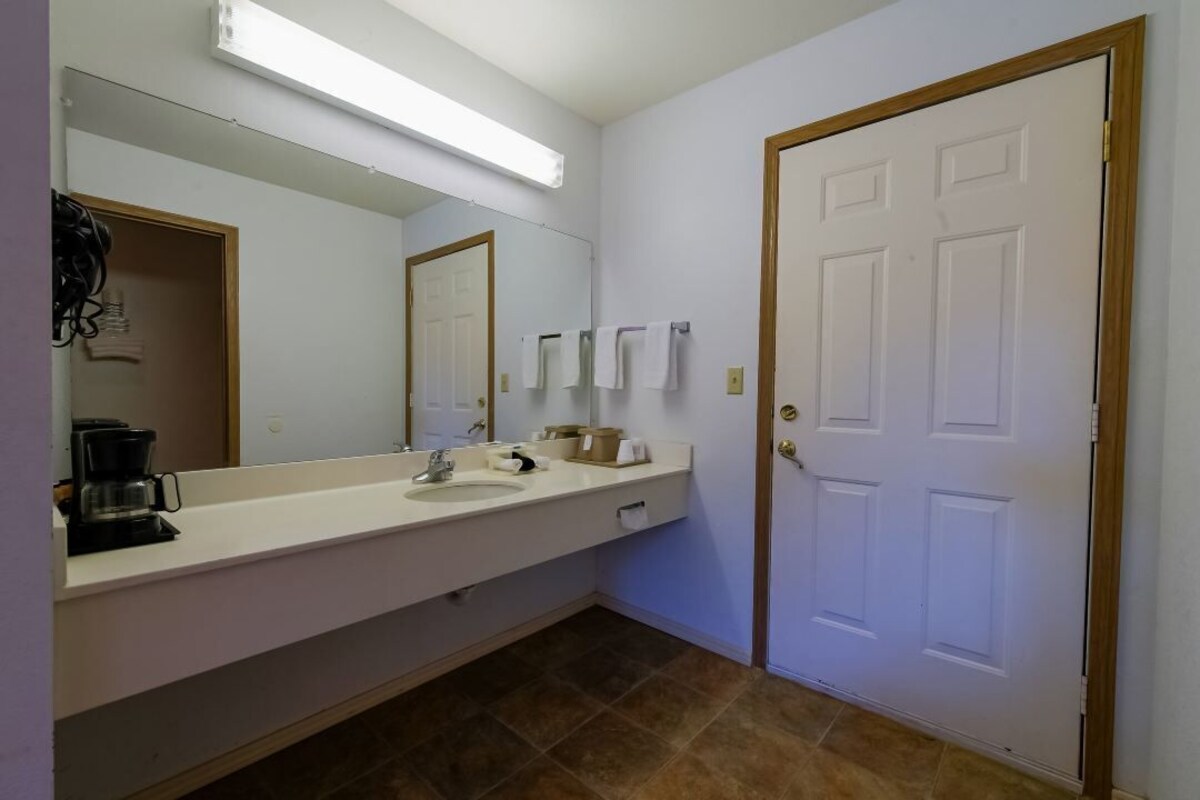 A bathroom with a white sink, mirror, and a door.