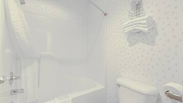 A bathroom with a bathtub, toilet, and a towel rack.