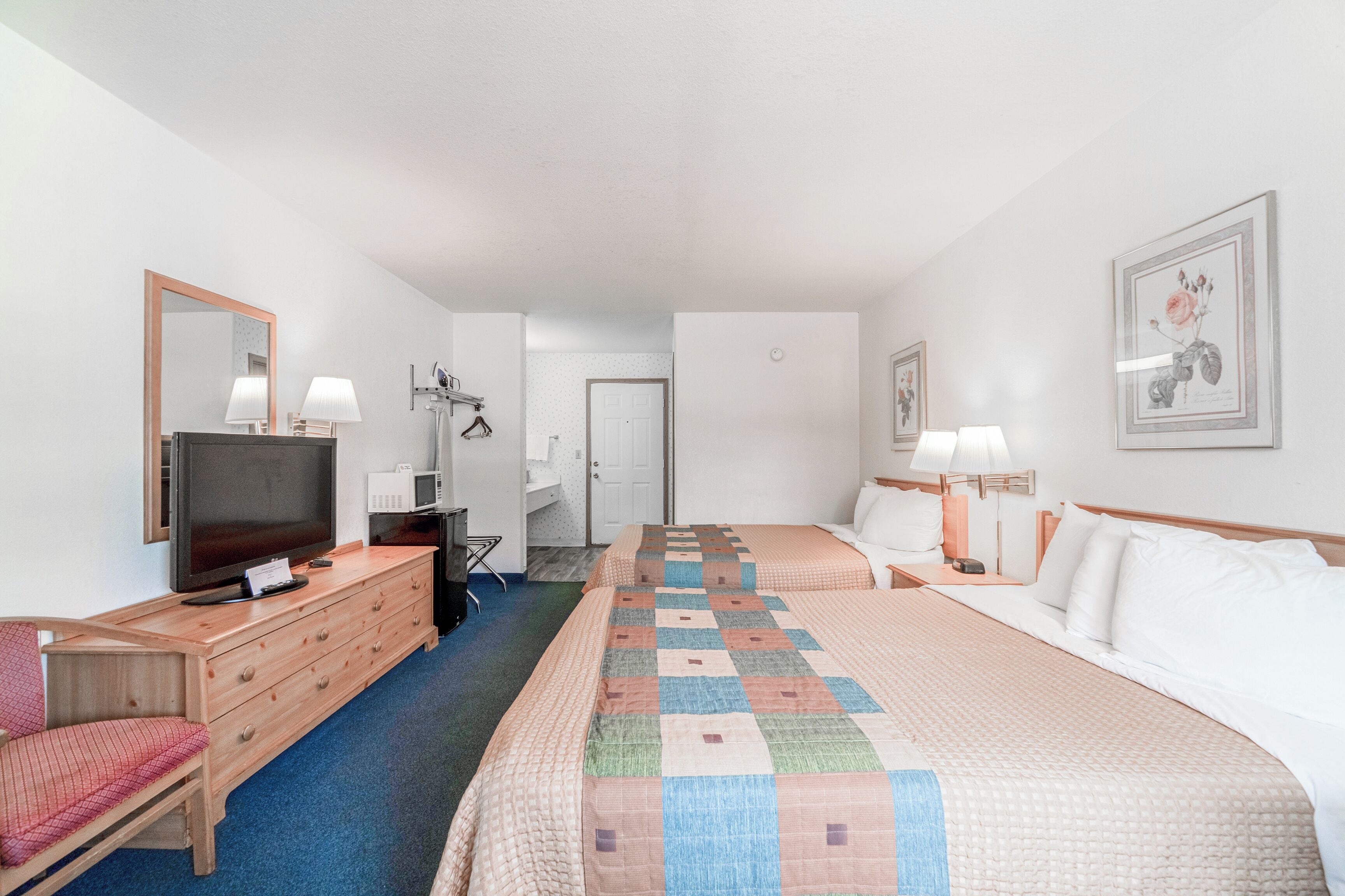 A hotel room with a large bed, a TV, a dresser, and a chair.