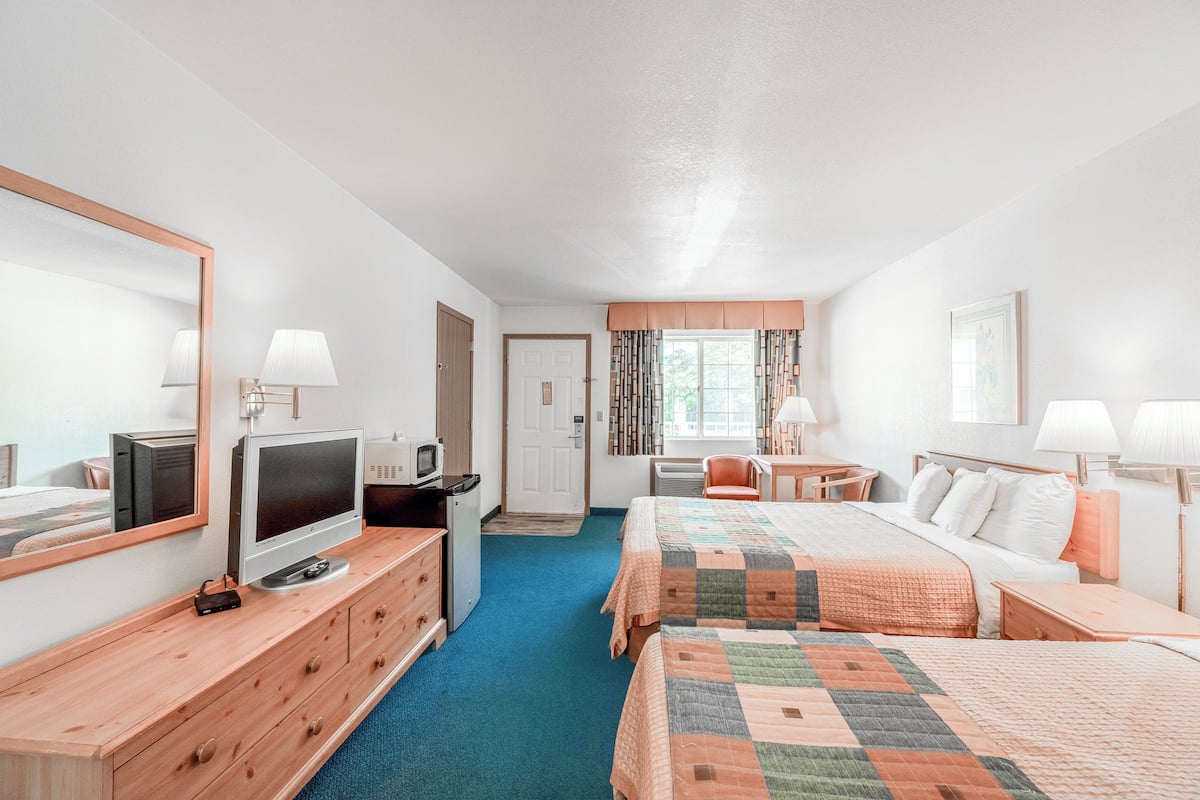 A hotel room with two beds, a TV, a desk, and a chair.