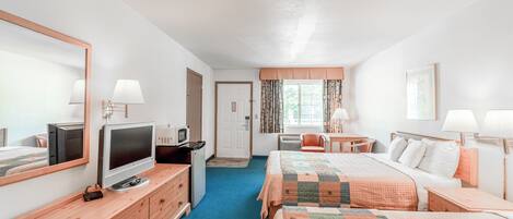 A hotel room with two beds, a TV, a desk, and a chair.