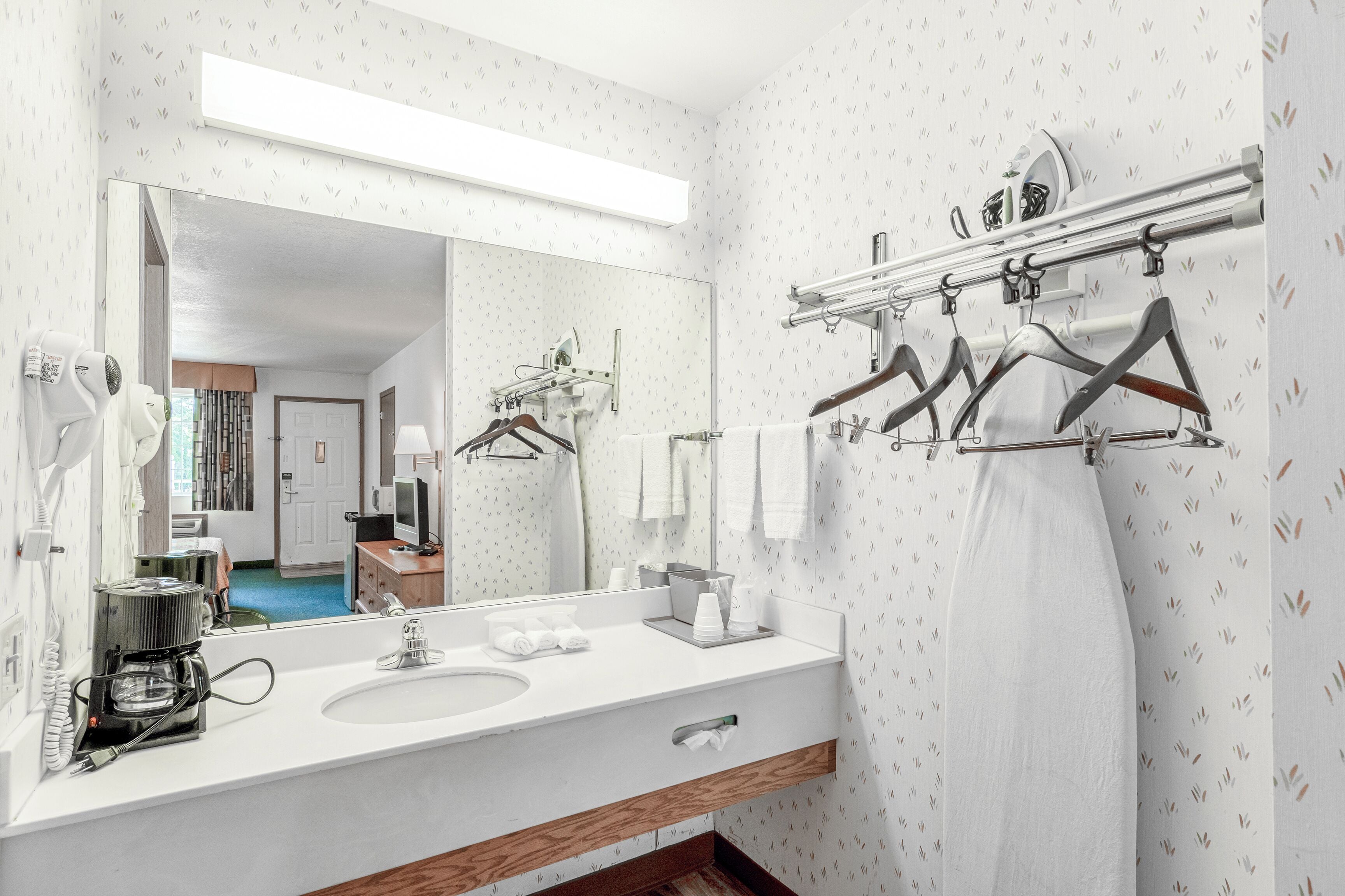 A modern bathroom with a large mirror, white sink, and towel rack.