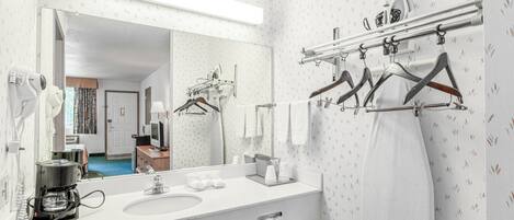 A modern bathroom with a large mirror, white sink, and towel rack.