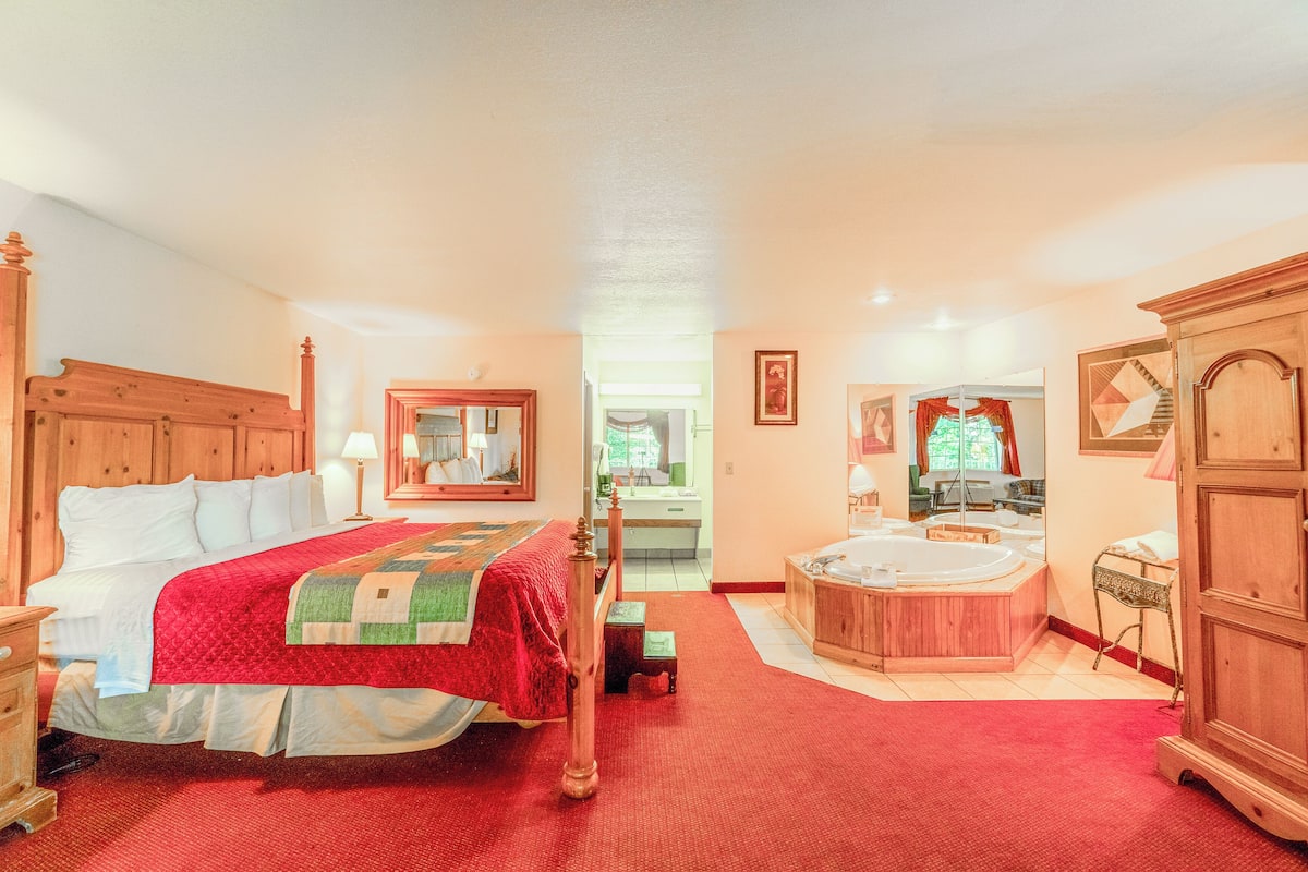 A spacious bedroom with a large bed, a wooden wardrobe, and a separate bathroom with a bathtub.
