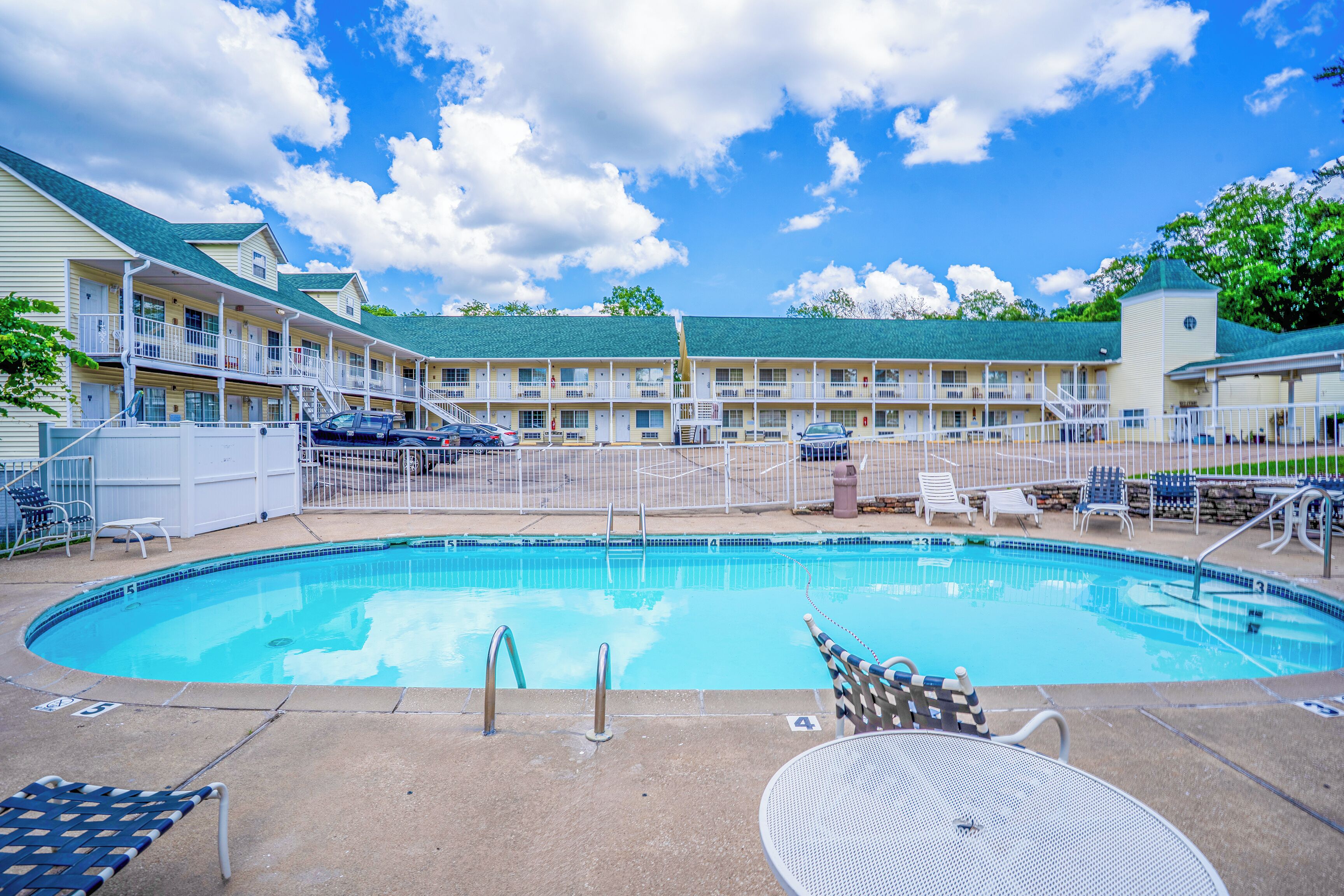Un motel con piscina, area salotto esterna e parcheggio recintato.