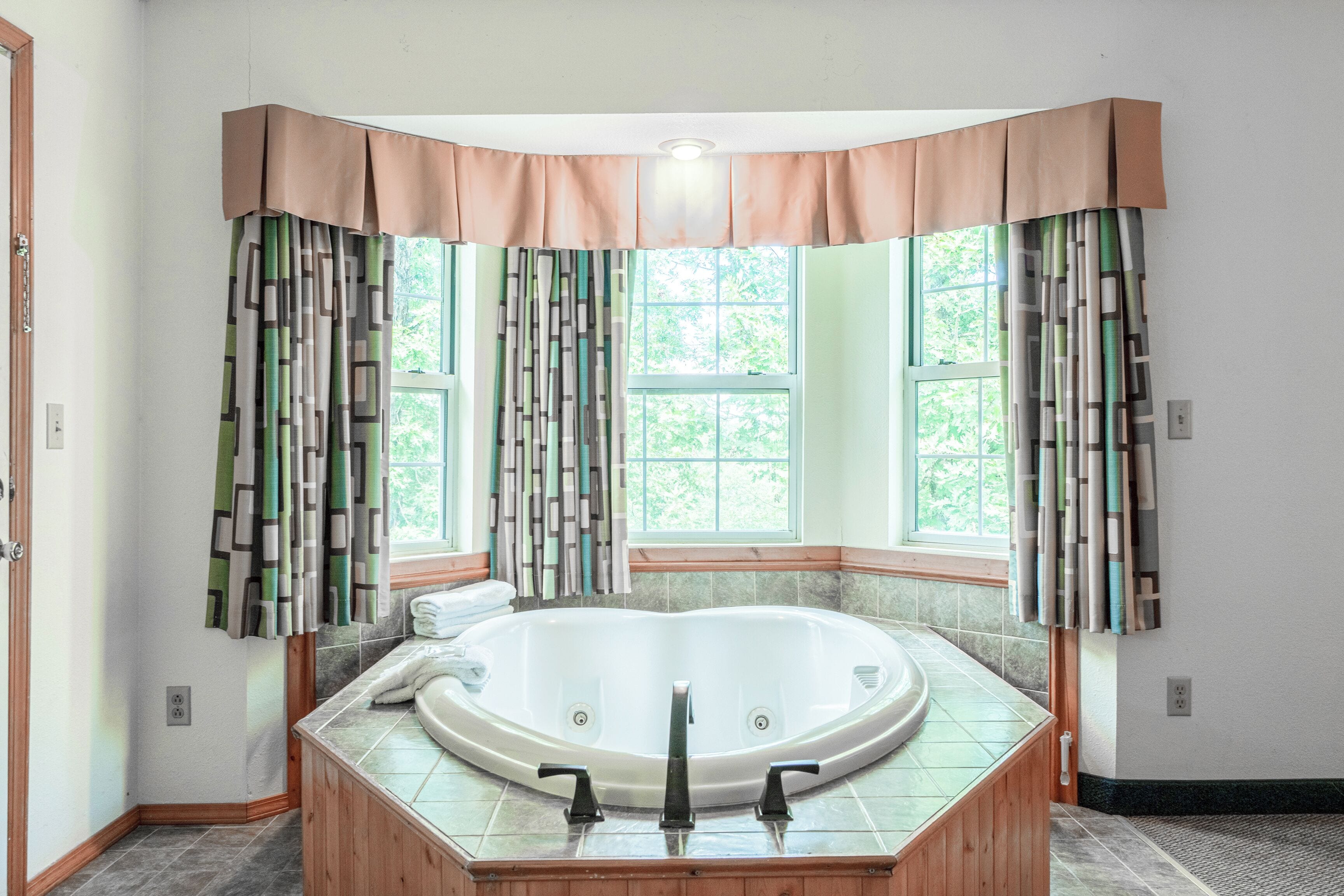 Ein Badezimmer mit freistehender Badewanne, einem Fenster mit Vorhängen und einem Handtuchhalter.