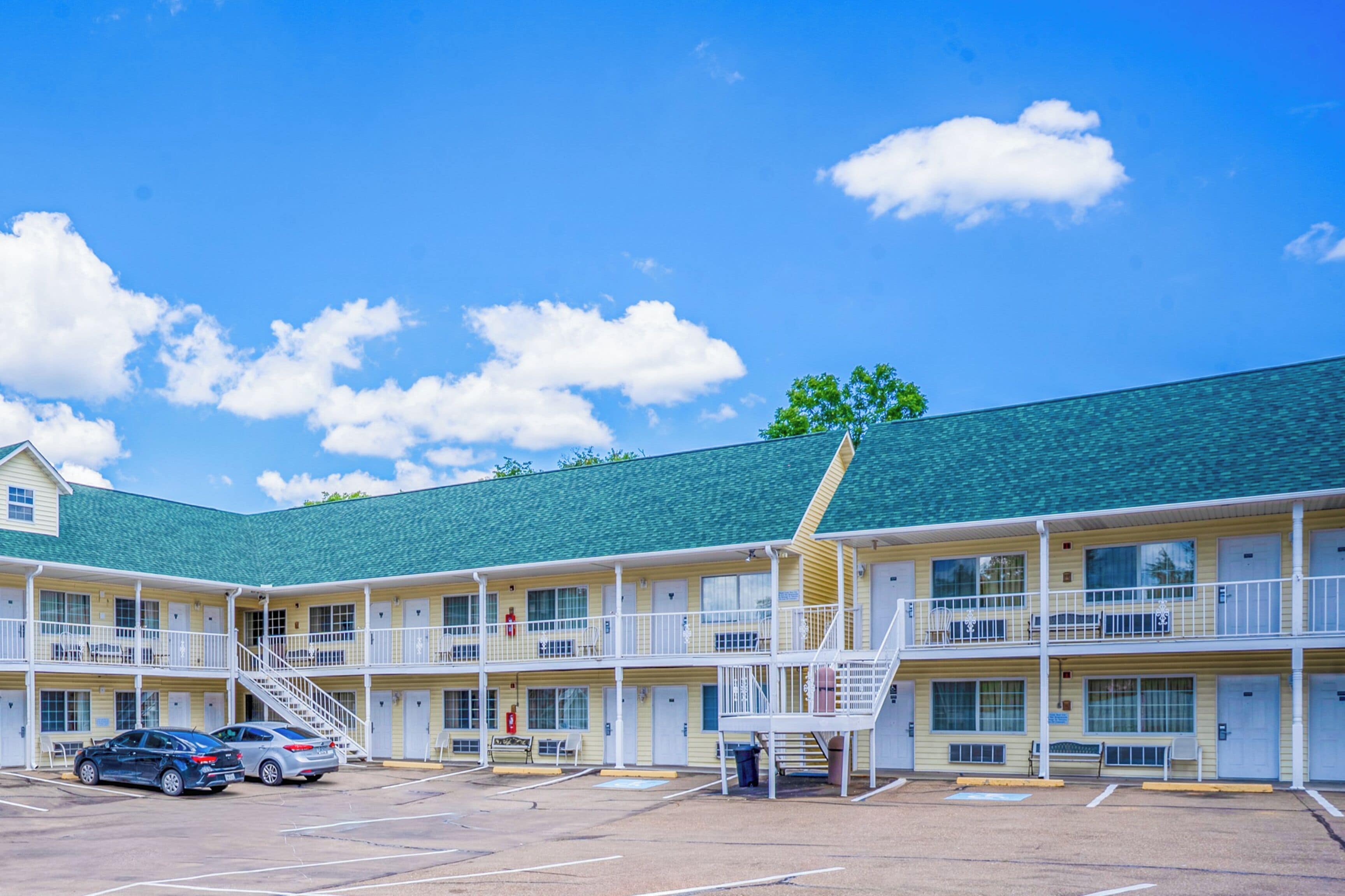 A motel with multiple floors, outdoor parking, and a green roof.