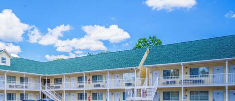 A motel with multiple floors, outdoor parking, and a green roof.