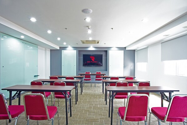 A conference room with tables and chairs, a projector screen, and a Red Planet logo on the wall.