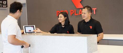 A reception desk with a digital screen, a clock, and a large 'R' logo on the wall.