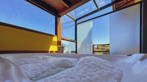 Banheira de hidromassagem com vista para o exterior atrav és de grandes janelas.
