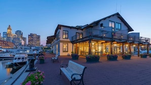 A waterfront hotel with a balcony, outdoor seating, and a view of the city skyline. - Boston Yacht Haven Inn & Marina (Boston)