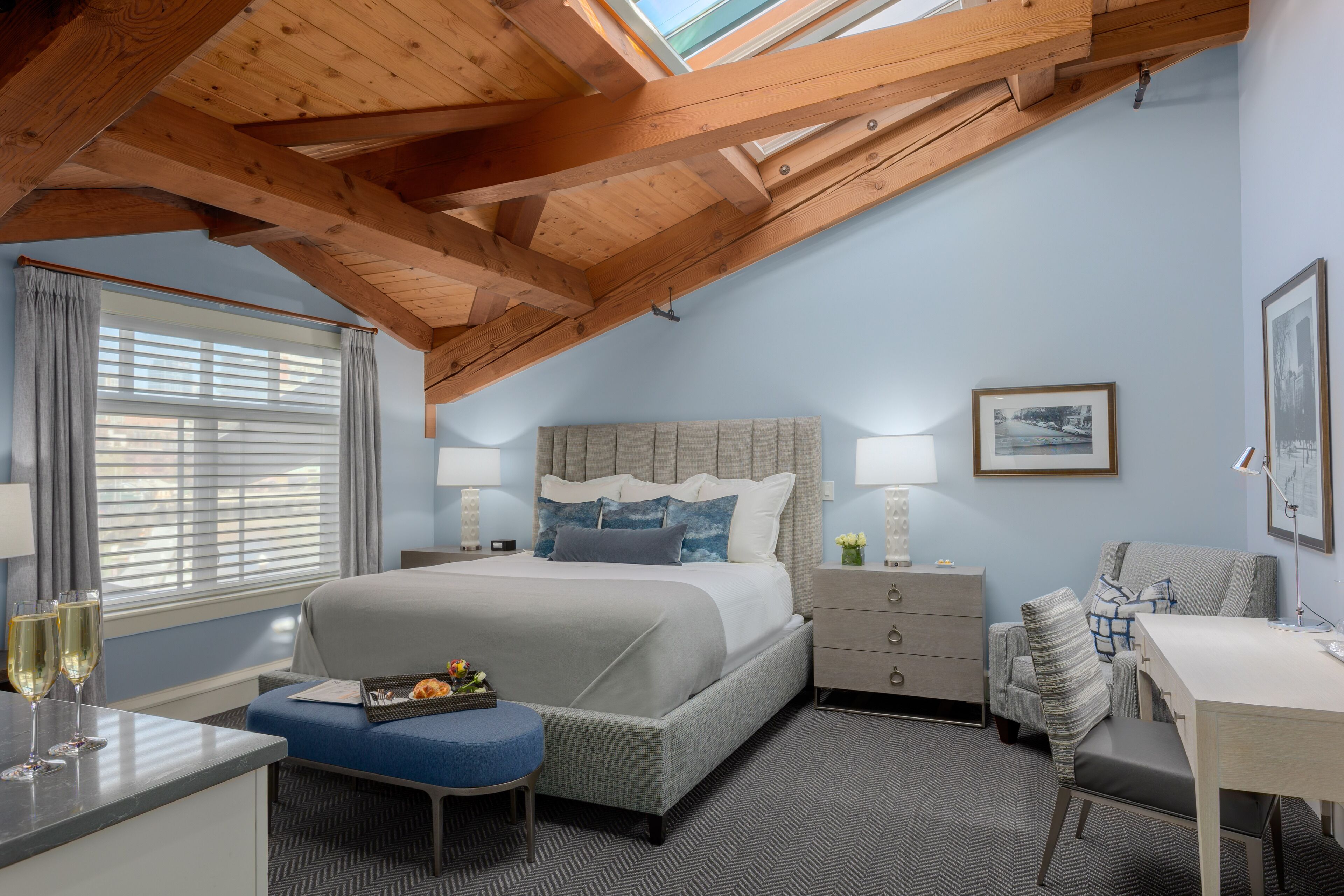 A bedroom with a bed, bedside tables, a desk, and a window with curtains.