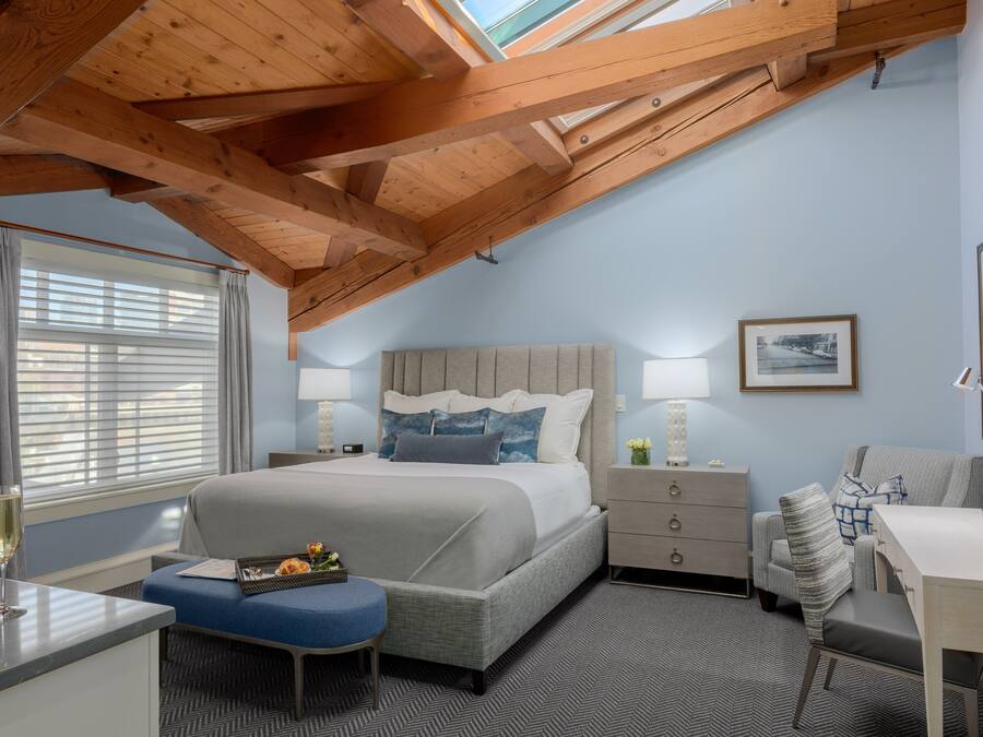 A bedroom with a bed, bedside tables, a desk, and a window with curtains.