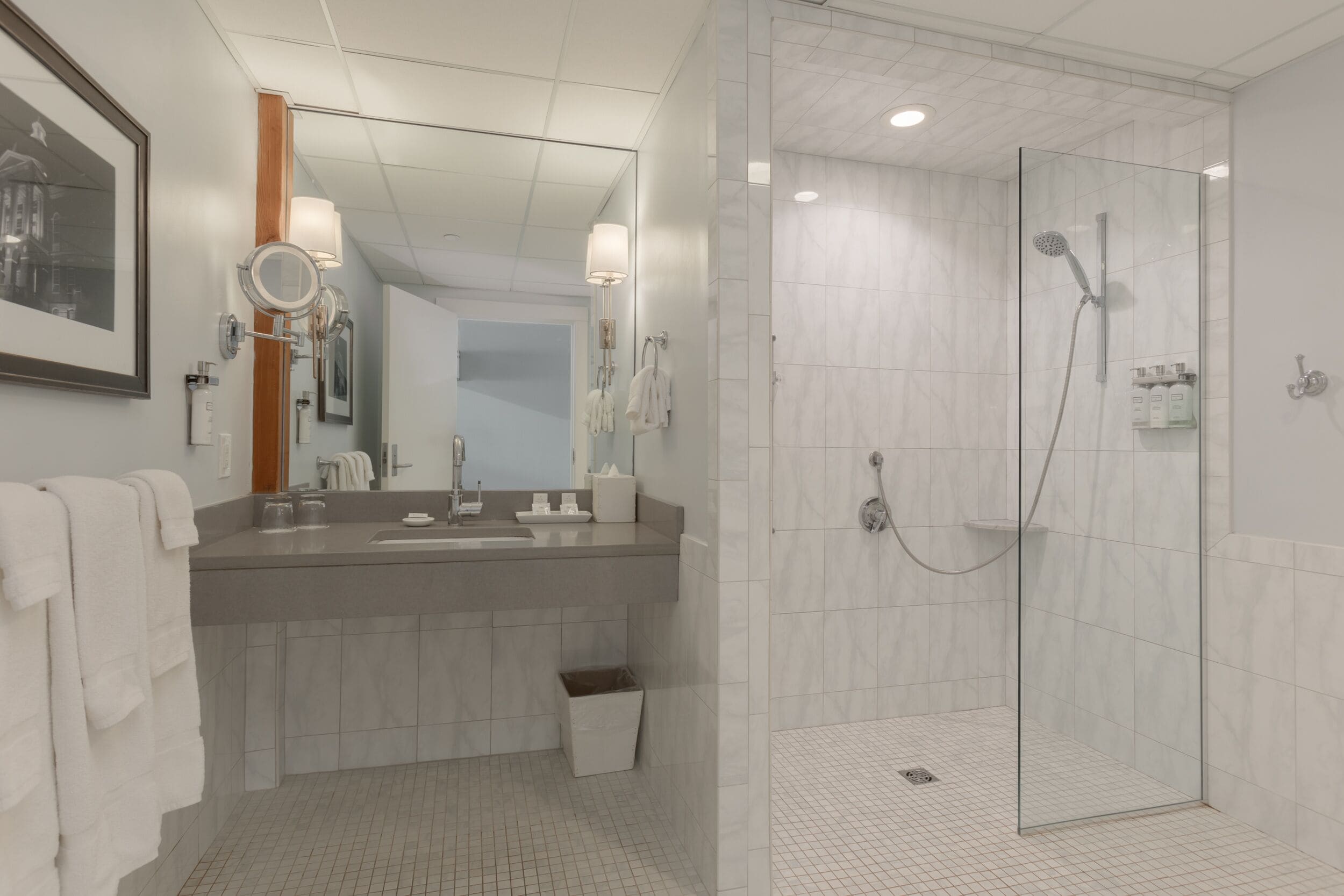 A modern bathroom with a large mirror, a sink, and a glass-enclosed shower.