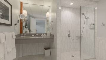A modern bathroom with a large mirror, a sink, and a glass-enclosed shower.