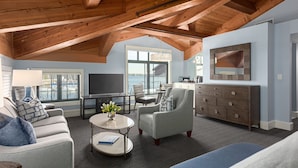 A spacious living room with a high ceiling, a large window overlooking a marina, a flat-screen TV, a dining area, and a cozy seating arrangement. - Boston Yacht Haven Inn & Marina (Boston)