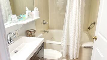 A bathroom with a sink, toilet, and bathtub. There is a shower curtain, a towel rack, and a trash can.