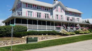 A two-story house with a balcony, a stone foundation, and a flag. - Harbor House Inn (Grand Haven)