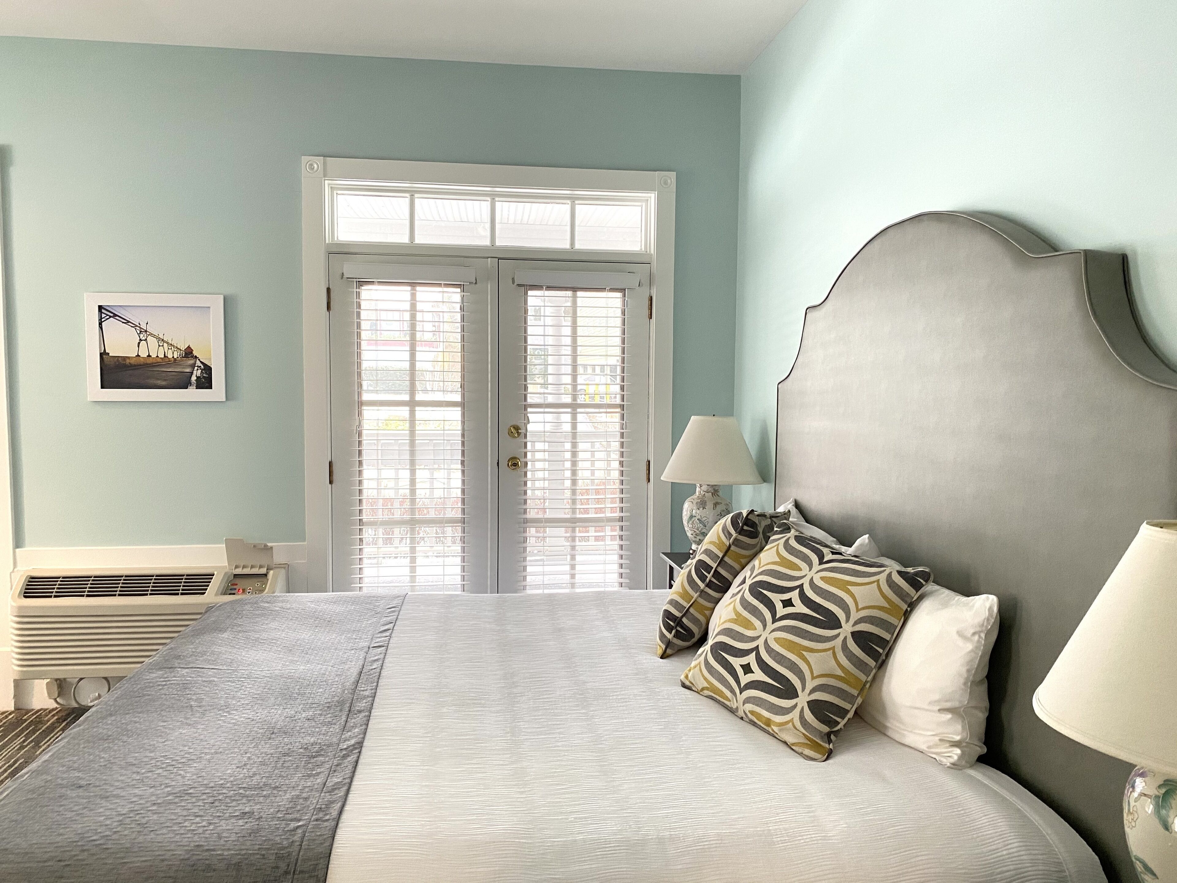 A bedroom with a bed, a nightstand, a lamp, and a window with blinds.
