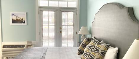 A bedroom with a bed, a nightstand, a lamp, and a window with blinds.