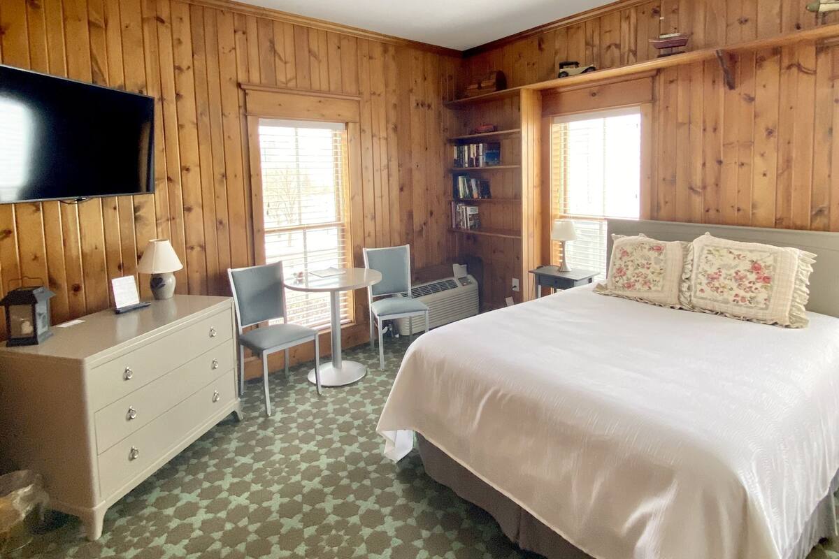 Una habitación con una cama, televisión, escritorio y una silla.