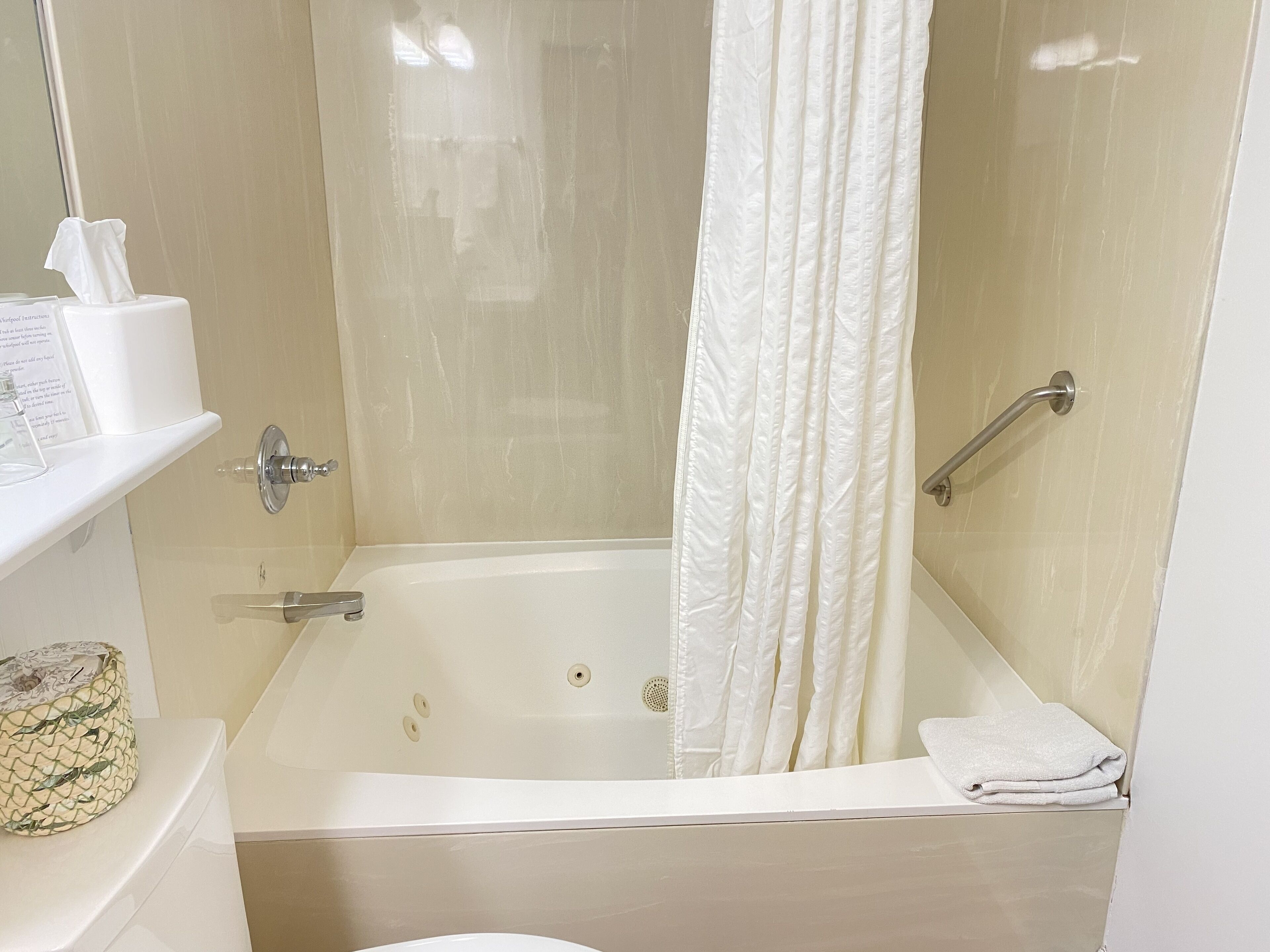 Un baño con bañera, cortina de ducha, toallero y retrete.