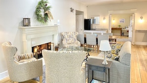 A living room with a fireplace, patterned chairs, a coffee table, and a television in the background. - Harbor House Inn (Grand Haven)